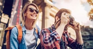 Um casal de jovens animados e tirando foto da paisagem para ilustrar o artigo sobre Consórcio de Serviços da Cresol