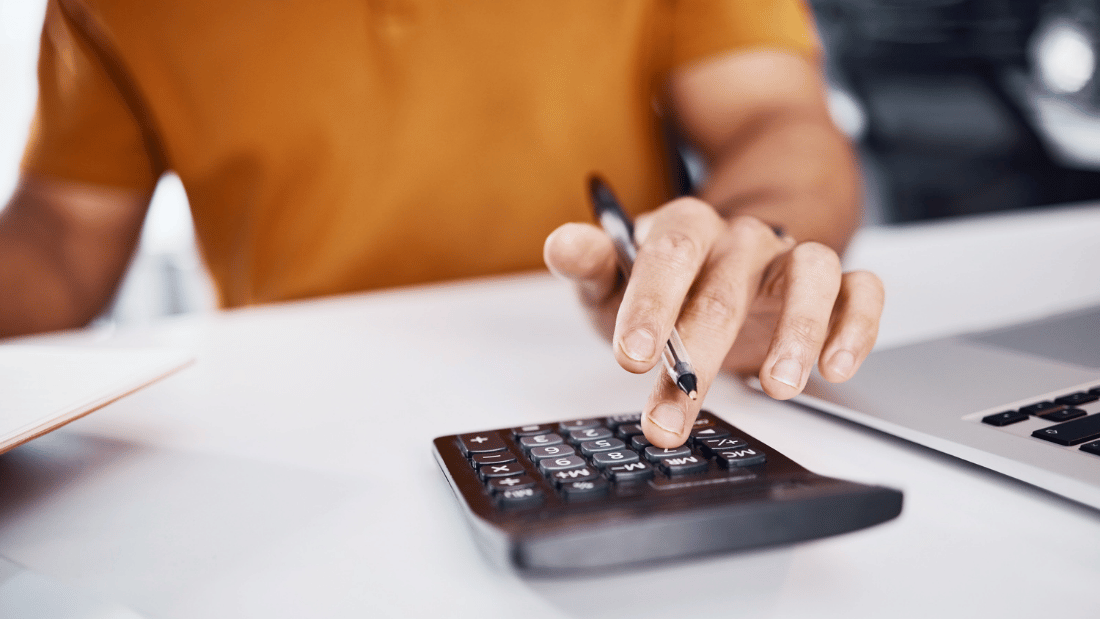Imagem que destaca a mão de um homem fazendo contas na calculadora para ilustrar artigo sobre o que é cheque especial