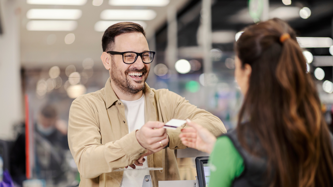 Foto de um homem fazendo um pagamento no caixa, usando cartão de crédito, para ilustrar o artigo da Cresol sobre Dia do Cliente