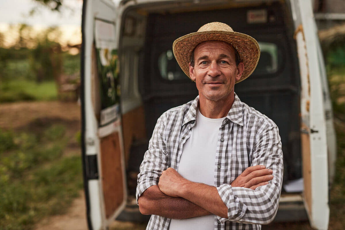 Agricultor em pé com braços cruzados sorrindo