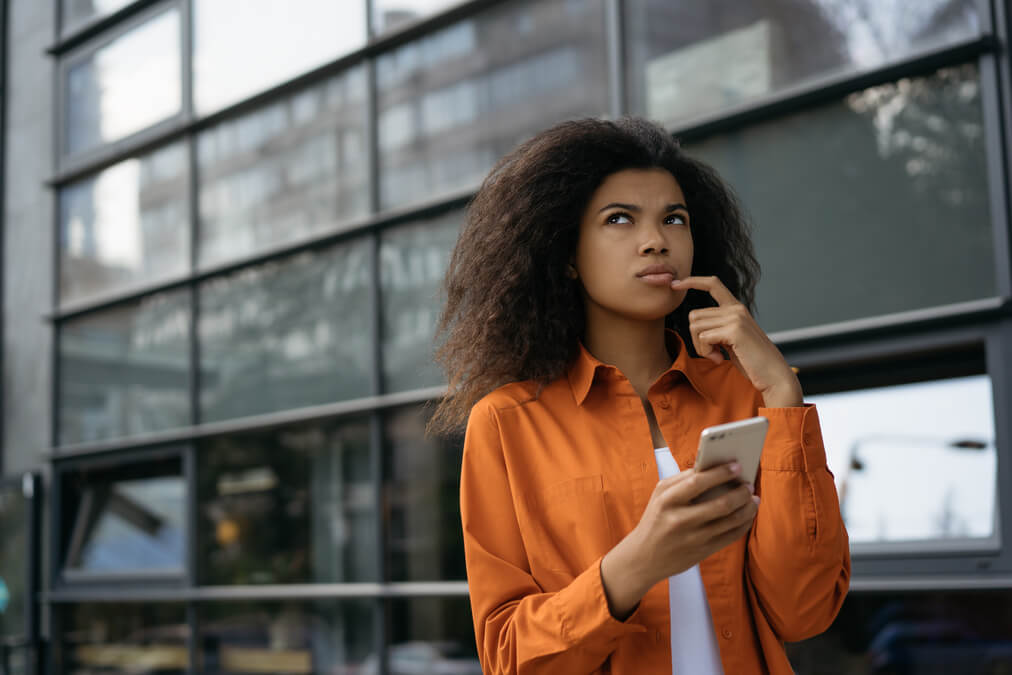 Pessoa pensativa com o celular na mão