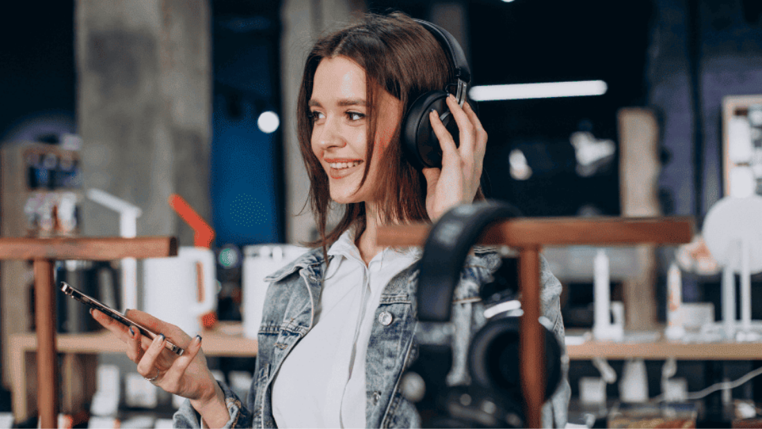 Jovem em uma loja de eletrônicos ouvindo música em headphones.